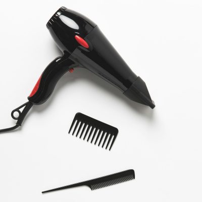 top view of hair dryer and two combs, on white